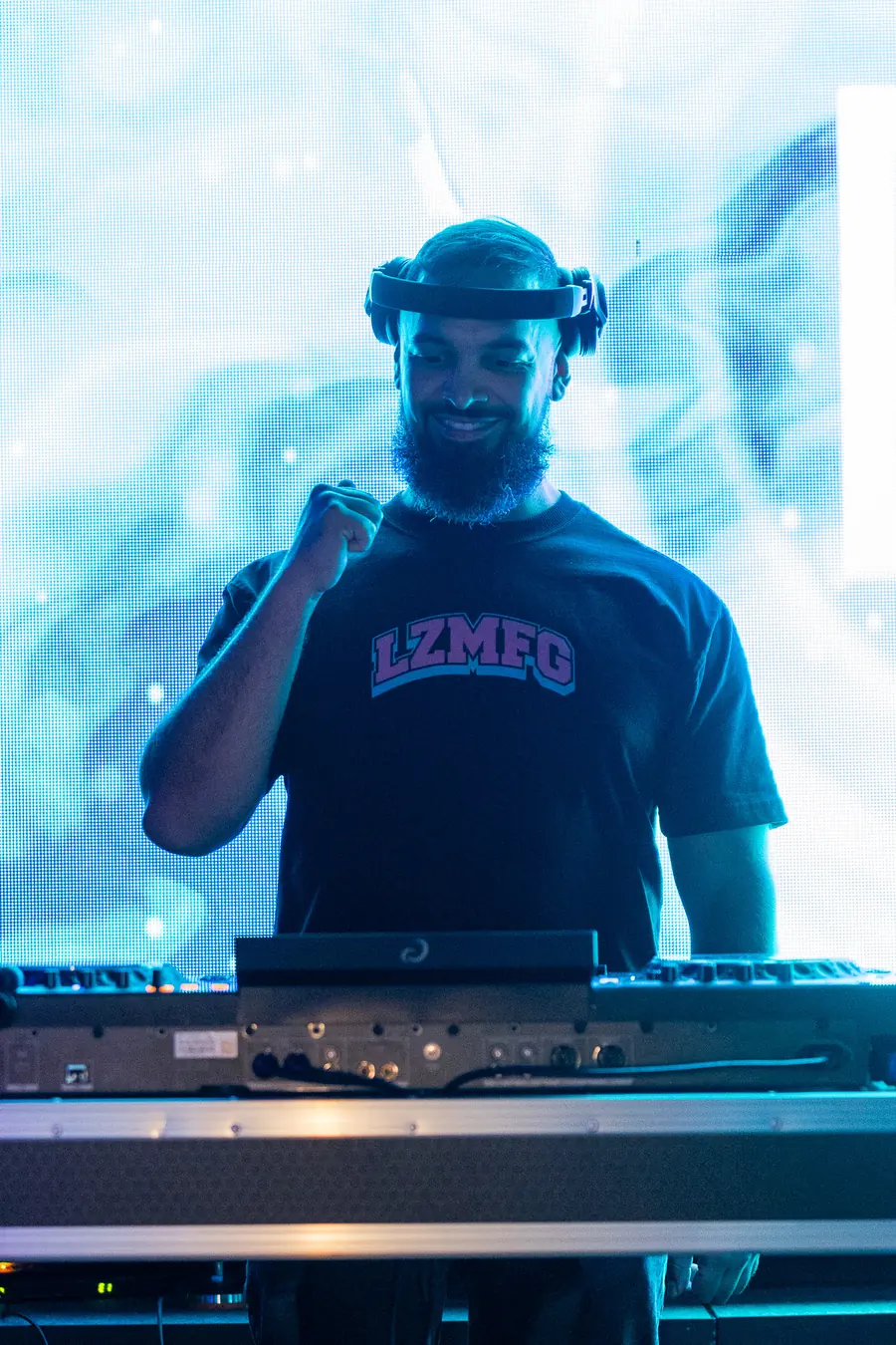 Smiling DJ in headphones backlit by a pale blue LED wall
