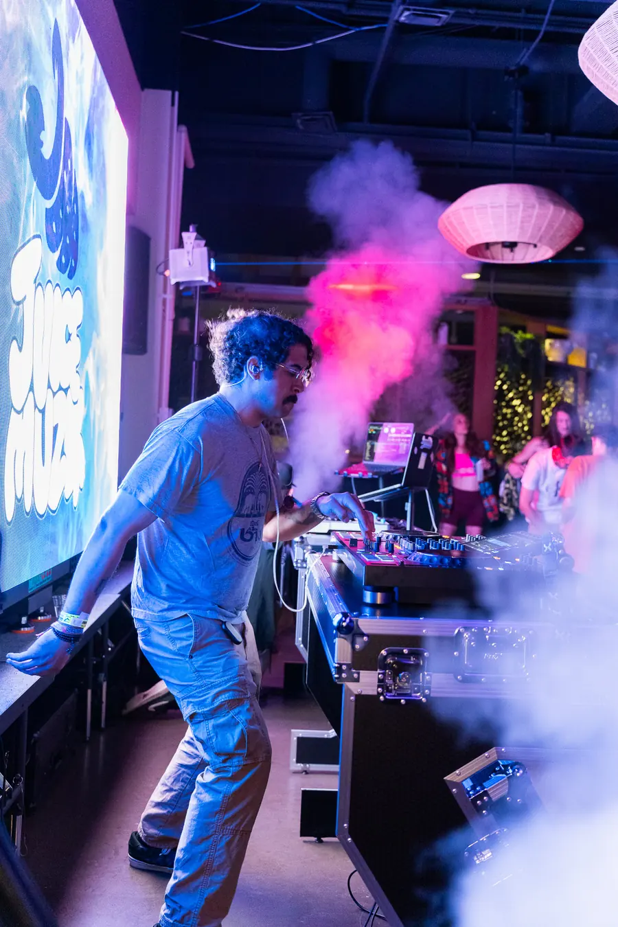 DJ dancing at the decks as a jet of pink smoke fires beside the LED wall